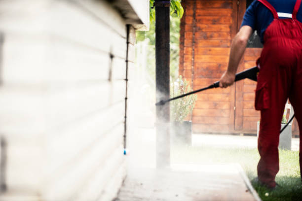 A brightness team member power washing a home siding.