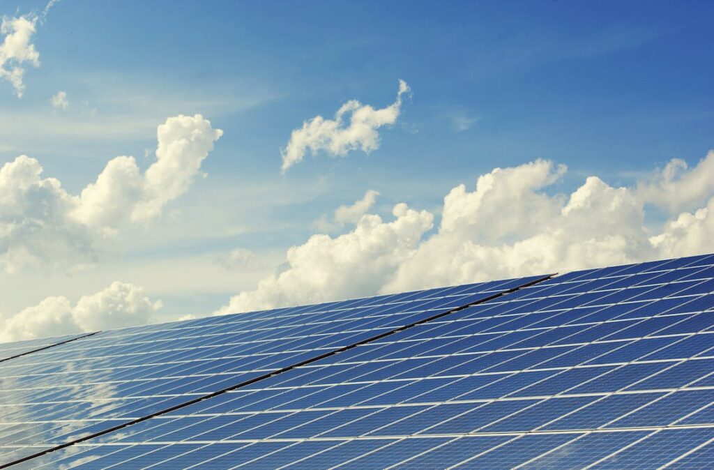 Alt Text: Clean solar panels installed on a roof angle against a vibrant blue sky with fluffy white clouds, showcasing optimal positioning for maximum sunlight absorption and energy efficiency.